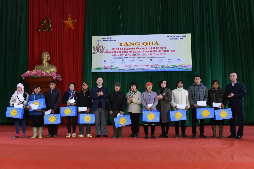 Phó Thống đốc Đào Minh Tú (đứng thứ 6 từ trái sang),  Phó Bí thư Thường trực Đảng ủy Cơ quan Ngân hàng Trung ương Lê Thị Mai Hương (đứng giữa) tặng quà cho người dân tại xã xã Sàng Ma Sáo và xã Dền Thàng