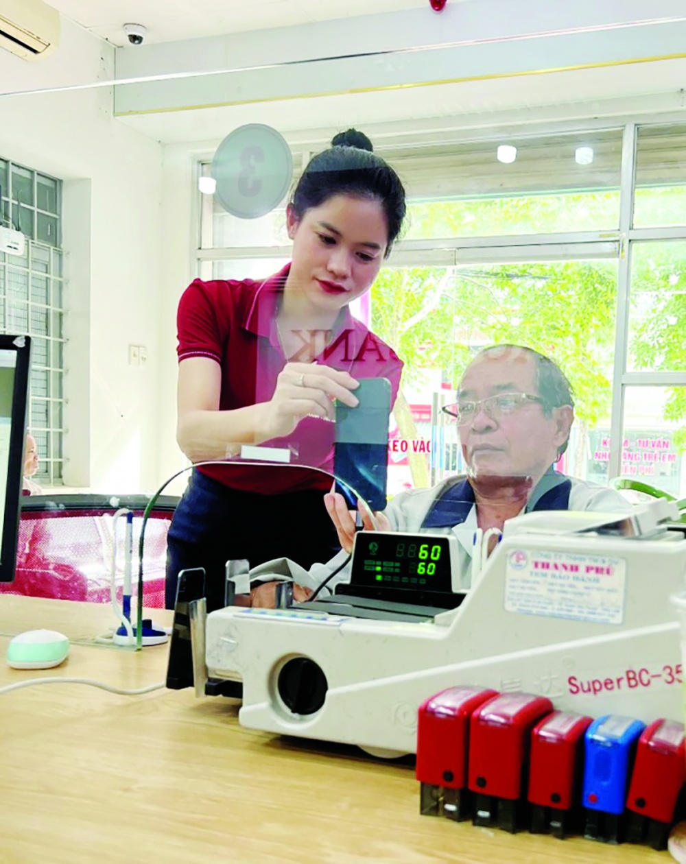 Giao dịch viên Agribank tỉnh Đắk Lắk hỗ trợ khách hàng đăng ký và xác thực dữ liệu sinh trắc học