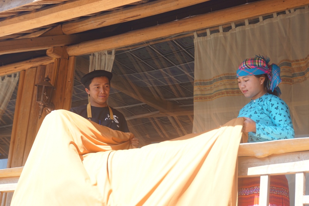 Hai vợ chồng anh Sùng Mí Phìn đang phơi chăn màn sau khi giặt tại khu homestay Chai To