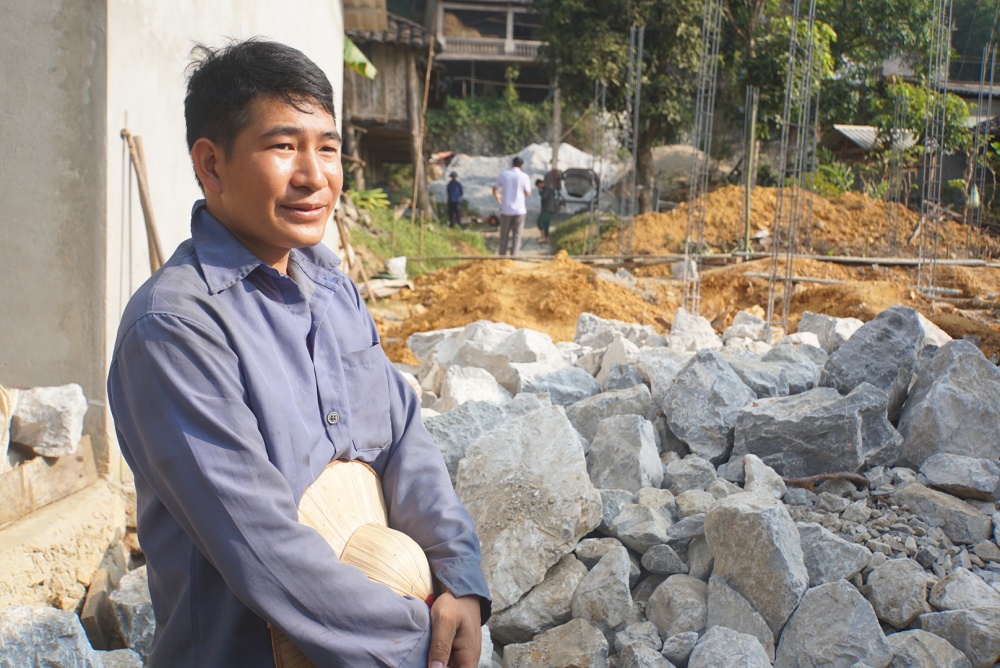 Anh Vùi Văn Nghiệp bên cạnh ngôi nhà mới đang được xây dựng