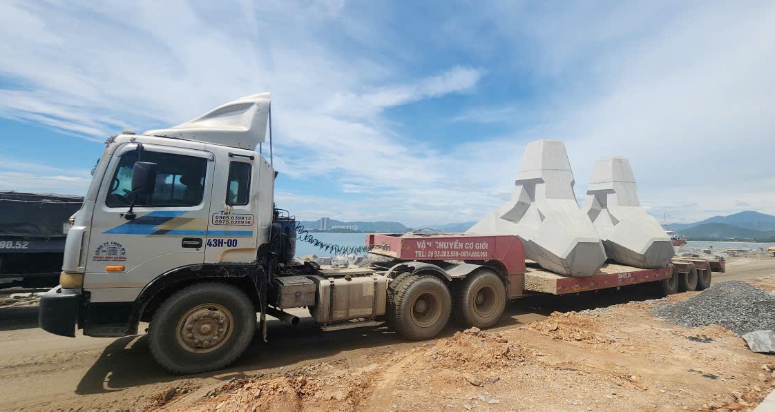 Trên con đường gập gềnh chưa hoàn thành này, mỗi ngày có đến hàng trăm lượt xe vận tài siêu trường, siêu trọng chở theo các khối bên tông lớn đi vào công trình.