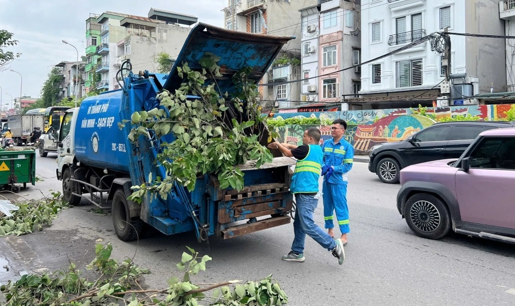 Các công nhân môi trường thu dọn hệ thống các cành, thân cây gãy đổ, xoá bỏ các điểm đen về rác thải trên địa bàn phường Hồng Hà, Hà Nội. Ảnh: KT&ĐT